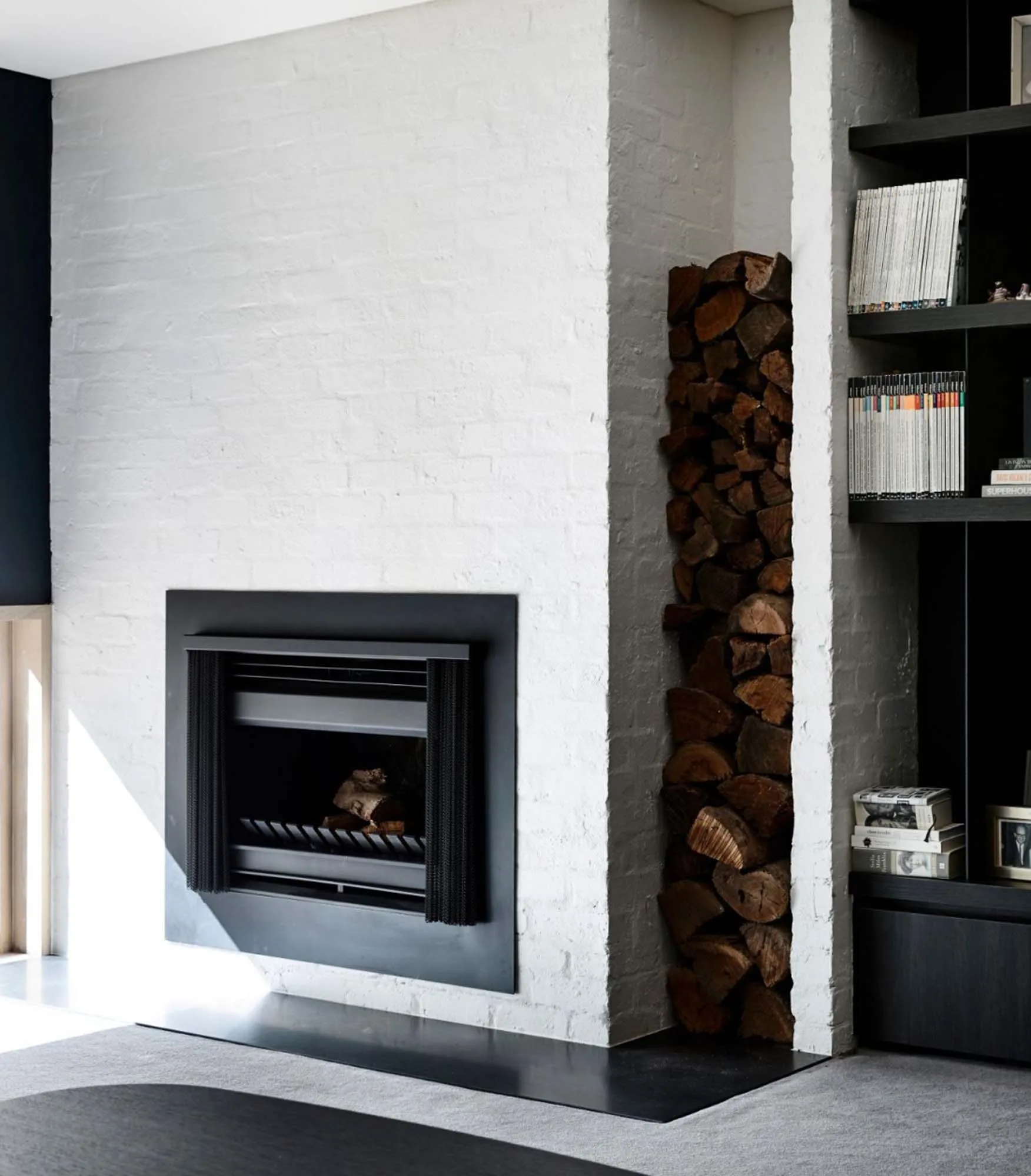 Brighton East Garden House — Indoor fireplace with a timber store